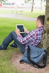 Student using his tablet pc outside leaning on tree | 유토이미지 | 상세페이지 | 베이직샵 | 사진 | 16752255