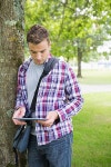Focused student leaning on tree using his tablet pc | 유토이미지 | 상세페이지 | 베이직샵 | 사진 | 16752335
