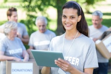 유토이미지 | Smiling volunteer brunette using tablet pc on a sunny day