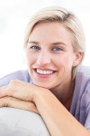유토이미지 | Pretty blonde woman sitting on the couch and smiling at the camera in the living room