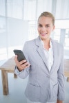유토이미지 | Smiling businesswoman sending a text at her desk in her office