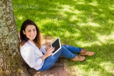 유토이미지 | Beautiful brunette using tablet pc in the park on a sunny day