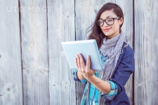 유토이미지 | Happy hipster holding a tablet pc against a wooden wall