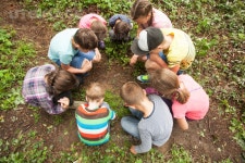 유토이미지 | A group of children who are considering something carefully, sitting in a circle on the background of nature