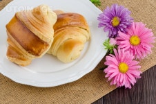 유토이미지 | Closeup of croissants with orange juice with flowers on wooden table
