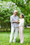 유토이미지 | Seniors in casualwear looking at one another while standing on green lawn in blooming park