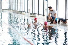 유토이미지 | Three happy females in swimwear having talk in water while their trainer consulting them
