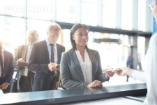 유토이미지 | Happy mixed-race businesswoman giving her documents to check-in manager by counter in airport