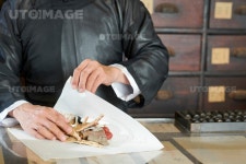유토이미지 | Hands of Chinese medicine practitioner wrapping dry treatment ingredients like roots and berries in paper sheet