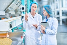 유토이미지 | Portrait of two young female workers wearing lab coats standing by conveyor line with macaroni in clean production... 
