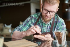 유토이미지 | Portrait of smiling modern barista holding handful of fresh coffee beans and checking quality of roast in artisan... 