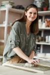 Waist up portrait of smiling female artisan kneading clay while working in pottery studio | 유토이미지 | 상세페이지... 