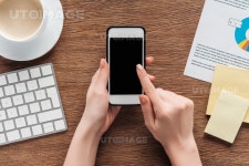유토이미지 | Cropped view of girl using smartphone with blank screen at workplace