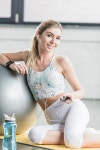 유토이미지 | smiling young woman in earphones resting and listening music with smartphone near fitness ball at gym