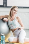 유토이미지 | smiling young woman in earphones resting and listening music with smartphone near fitness ball at gym