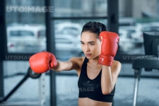 유토이미지 | young female boxer in gloves making heat at gym