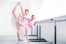 유토이미지 | beautiful adult and little ballerinas stretching and smiling at camera in ballet school