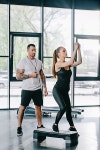 young sportswoman doing step aerobics exercise and male personal trainer with timer in hand at gym | 유토이미지 | 상세페이지... 
