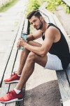 유토이미지 | young sportsman with bottle of water sitting on bench at sport playground