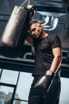 유토이미지 | low angle view of handsome tired boxer leaning on punching bag in gym