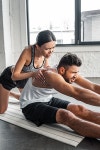 유토이미지 | female trainer helping young sportsman stretching on yoga mat in gym