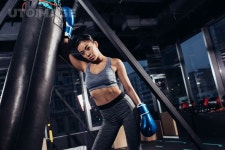 유토이미지 | sexy asian girl in boxing gloves standing near punching bag at gym
