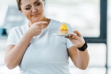 유토이미지 | cheerful overweight woman pointing with finger at tasty cupcake in gym