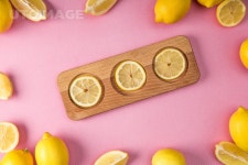 유토이미지 | top view of fresh lemon slices on wooden board with lemons around on pink background