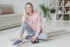 유토이미지 | attractive woman sitting on yoga mat with dumbbells at home