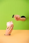 유토이미지 | cropped view of woman holding small hammer and pink piggy bank on green and orange