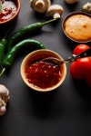 유토이미지 | top view of tasty sauces in bowls near ripe cherry tomatoes, green chili peppers and mushrooms on black