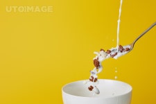 유토이미지 | spoon with assorted cereal and milk splashes above bowl isolated on yellow
