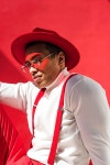 유토이미지 | fashionable mixed race man in hat, glasses and suspenders posing on red