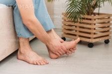 유토이미지 | cropped view man touching foot while sitting on bed and suffering from pain