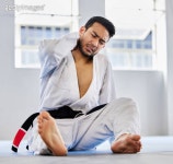 Injury, karate and man with knee pain after an accident in martial arts training in a wellness studio or dojo. Fitness, taekwondo... 