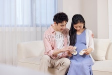  아기 용품을 들고 달콤하게 상호 작용하는 젊은 기대 부부
