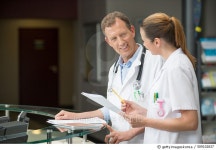 509102837 | 게티이미지코리아 | Two doctors discussing at hospital reception desk Royalty-Free 이미지