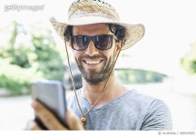589935855 | 게티이미지코리아 | Smiling man wearing straw hat and sunglasses holding cell phone Royalty-Free 이미지
