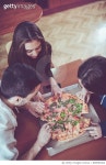 898995452 | 게티이미지코리아 | Group of Smiling Roommates Friends Sharing a Pizza at Home Royalty-Free 이미지