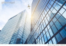 965361154 | 게티이미지코리아 | commercial airplane flying over modern skyscrapers Royalty-Free 이미지