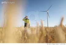 1125577809 | 게티이미지코리아 | Engineer standing in a field at a wind farm talking on cell phone Royalty-Free 이미지