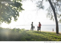 640915764 | 게티이미지코리아 | Mature couple pause with bicycles at beach edge, sea Royalty-Free 이미지
