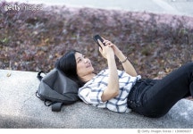 1308898207 | 게티이미지코리아 | Young woman playing mobile game in the park Royalty-Free 이미지