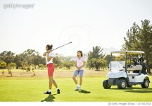 1371912334 | 게티이미지코리아 | Woman teeing off while friend standing at golf course against clear sky Royalty-Free 이미지