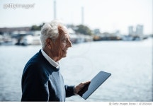 1372503420 | 게티이미지코리아 | Smiling senior man with white hair holding tablet PC on sunny day by the water Royalty-Free... 
