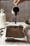 Chocolate cake preparation on kitchen counter human hand pouring chocolate. Ready to be baked Royalty-Free 이미지