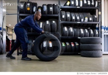 1489285854 | 게티이미지코리아 | Mechanic changing a flat tire and carrying a wheel at a repair garage Royalty-Free 이미지