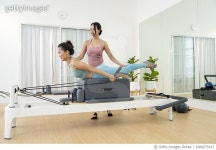 1660275013 | 게티이미지코리아 | Pretty woman in sportswear doing pilates exercise on reformer with trainer assisting. Royalty... 