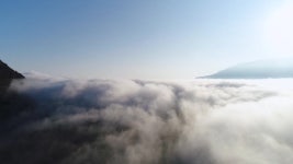 구름 위의 아름다운 일출, 산 정상에서 바라보는 전망. 발사. 푸른 맑은 하늘과 밝은 태양을 배경으로 두꺼운 구름의 느린 움직임을 위한... 
