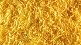 시계 방향으로 천천히 회전하는 익히지 않은 국수의 배경 - 위쪽 뷰, 클로즈업. 말린 당면의 질감이 돌아갑니다. 로우 키 라이트를 곁들인... 